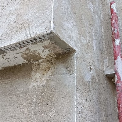 קיר עם טיח מתקלף וצינור צבוע אדום