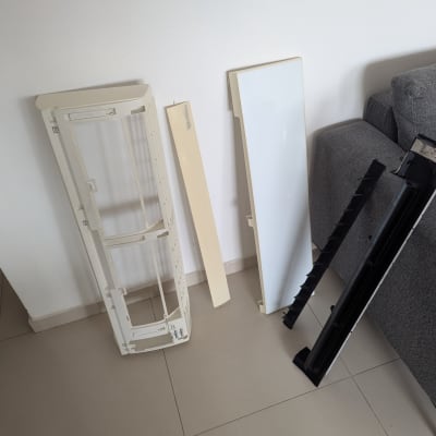 חלקי מזגן מפורקים על הרצפה ליד ספה אפורה