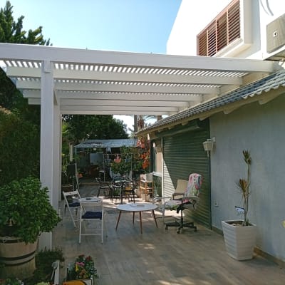 פרגולה לבנה בגינה עם ריהוט גן וצמחים