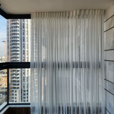 וילון לבן שקוף תלוי על חלון זכוכית