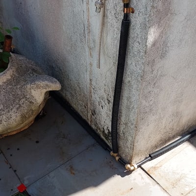 ברז מים עם צינור שחור על קיר חיצוני