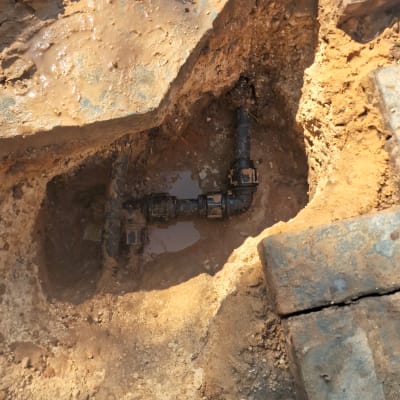 צינור מים חשוף בתוך בור חפירה באדמה