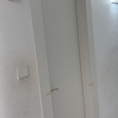 דלת לבנה עם ידית כסופה בקיר לבן