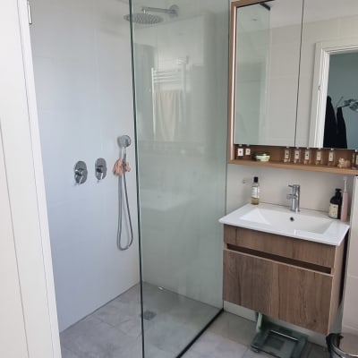 מקלחון זכוכית בחדר אמבטיה מודרני עם כיור ומראה