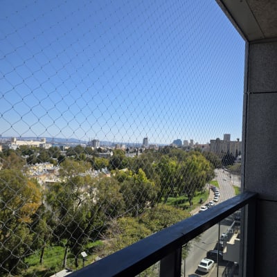 רשת יונים מותקנת על מרפסת עם נוף לעיר