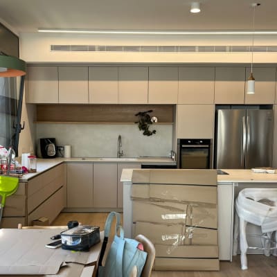 מטבח עם ארונות, מקרר, כיסאות עטופים, קופסאות קרטון