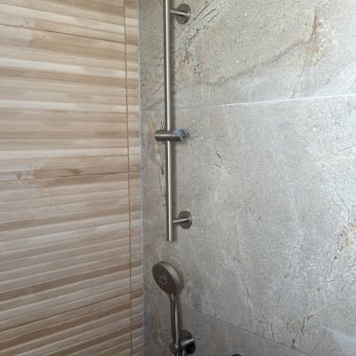 מקלחת חדשה עם ראש מקלחת מודרני וברזים על קיר אריחים