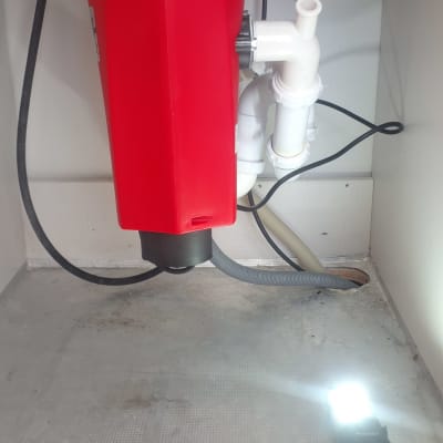 מתקן אדום מתחת לכיור עם צינורות חיבור