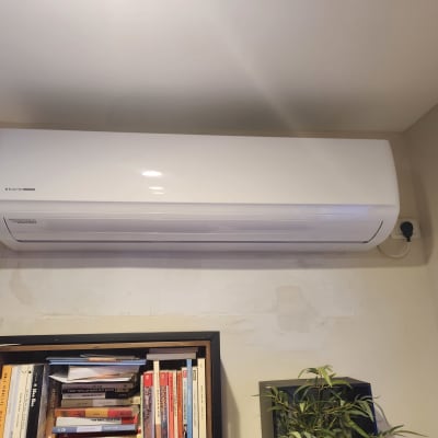 מזגן מותקן על קיר מעל מדף ספרים