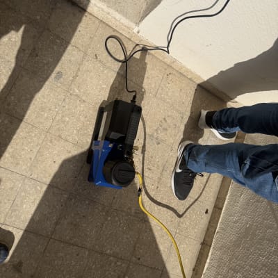 מכשיר עם כבל צהוב על רצפה, רגליים נראות בצד