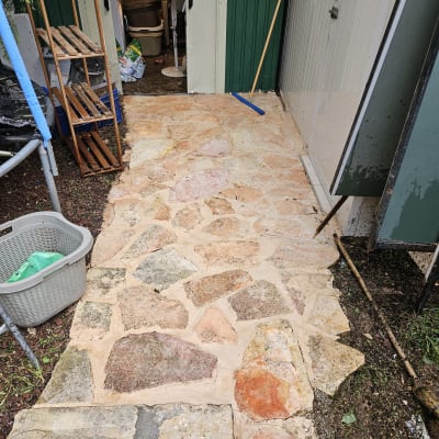 מטאטא כחול על שביל אבן ליד מחסן