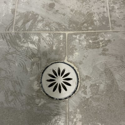 ניקוז עגול ברצפת אריחים עם שאריות חומר