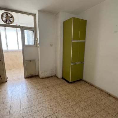 ארון ירוק גבוה בחדר ריק עם רצפת אריחים