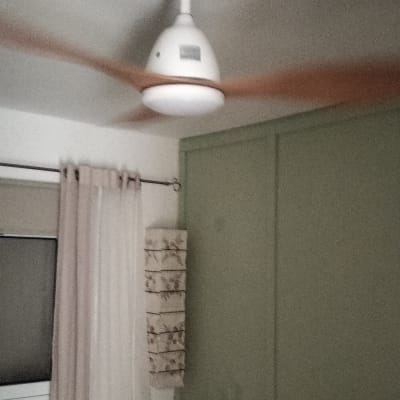 מאוורר תקרה בחדר שינה עם מיטה וכריות