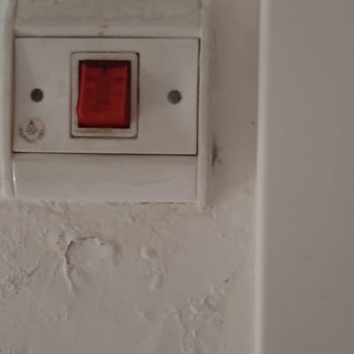 מתג חשמלי עם כפתור אדום על קיר