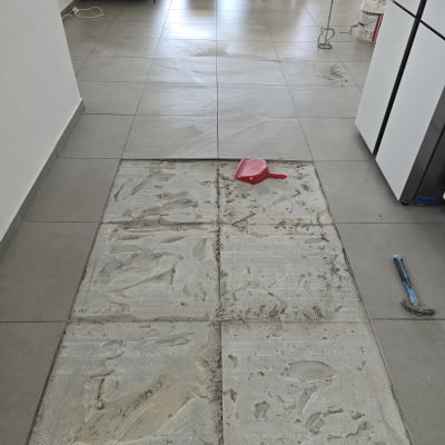 רצפה עם אריחים מוסרים, פטיש ומטאטא אדום