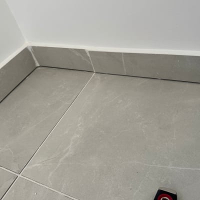 ריצוף קרמיקה בפינת חדר עם כלי מדידה קטן.