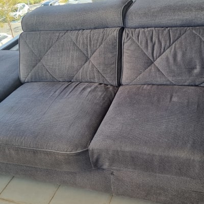 ספה אפורה עם ריפוד מרופד, נראית נקייה ומסודרת.