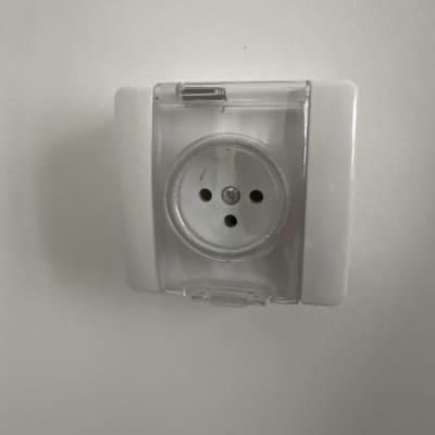 שקע חשמלי עם כיסוי שקוף על קיר לבן