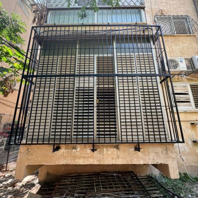 סורגים שחורים על חלונות בניין עם תריסים