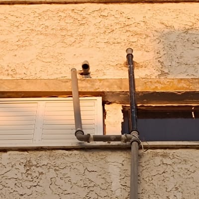 צינורות מתכת על קיר בניין עם חלון תריסים