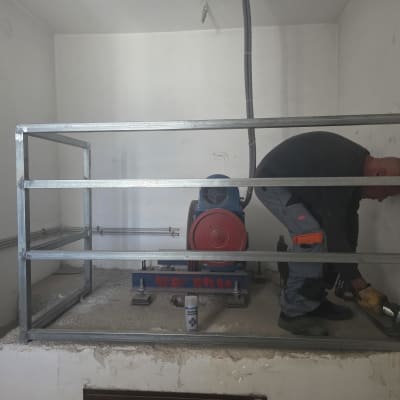 אדם עובד על מסגרת מתכת בחדר קטן