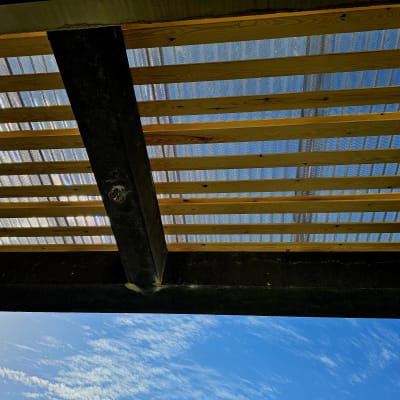 קורות עץ עם כיסוי פלסטיק שקוף בגינה