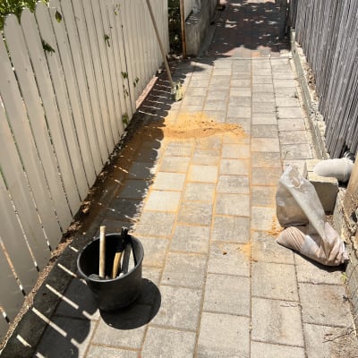 כלי עבודה ודלי על שביל מרוצף בחצר