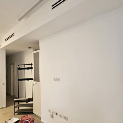 דלי צבע ומברשת על רצפה ליד קיר לבן