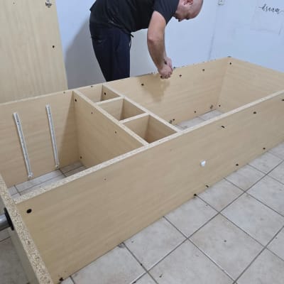 אדם מרכיב רהיט מעץ על רצפת אריחים