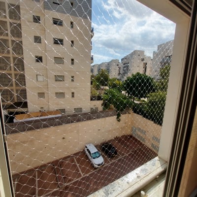 רשת יונים מותקנת על חלון עם נוף לבניינים