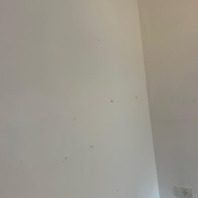 קיר לבן עם סימנים קטנים ושקע חשמל