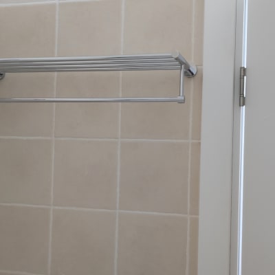 מתלה מגבות מתכת מותקן על קיר אריחים