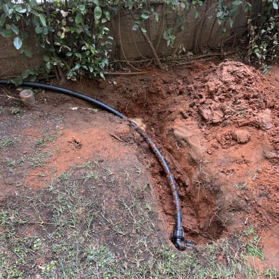 צינור שחור מונח בתעלה באדמה חפורה