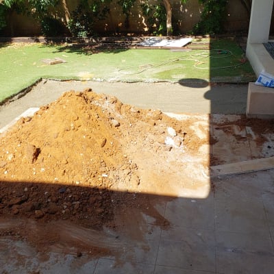 ערימת עפר בחצר עם דשא מלאכותי ועצים ברקע