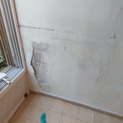 קיר עם סדקים ותיקוני טיח, מטלית על הרצפה