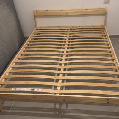 מיטה מעץ עם מזרן וכלי עבודה על הרצפה