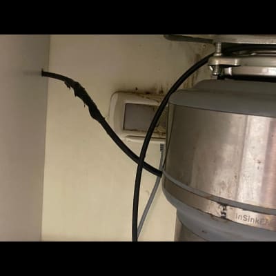 חוט חשמל מחובר למכשיר מתכת מתחת לכיור