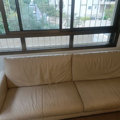 ספת עור בצבע קרם נקייה ומתוחזקת בסלון הבית