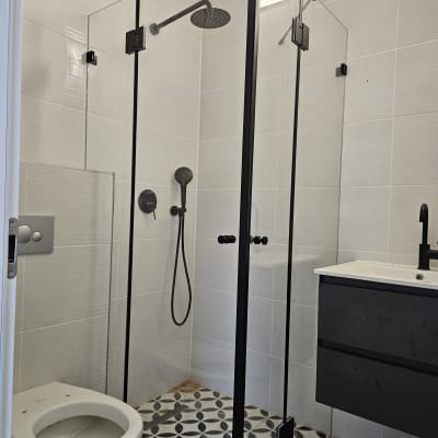 מקלחון זכוכית עם ראש מקלחת עגול וברז שחור