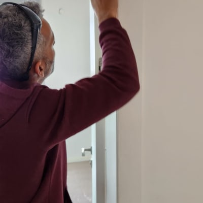 אדם מתקין ציר בדלת לבנה