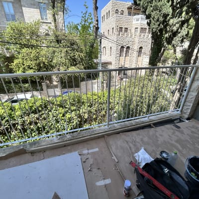 מעקה מתכת לבן על מרפסת עם כלים לצביעה