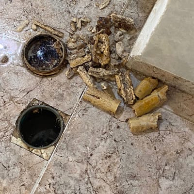 פתח ניקוז פתוח עם פסולת צינורות על הרצפה