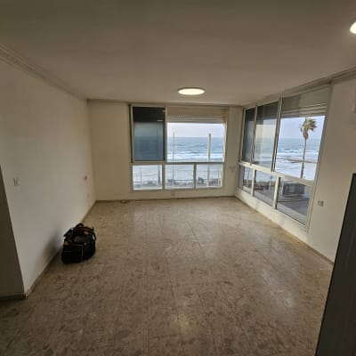 חדר ריק עם חלונות גדולים ונוף לים, תיק כלים על הרצפה