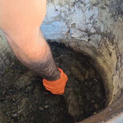 יד עם כפפה כתומה בתוך בור, עבודה בתחום VacuumTruck