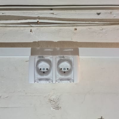 שני שקעים חשמליים עם כיסויים שקופים על קיר לבן