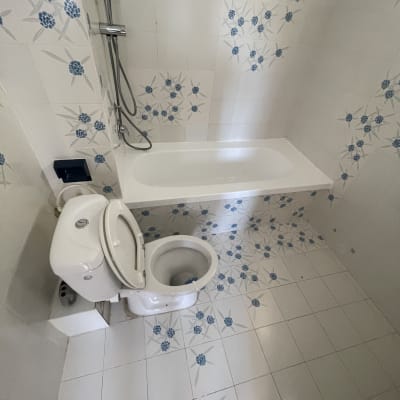 חדר רחצה נקי ומתוחזק עם אריחים פרחוניים, אמבטיה ואסלה