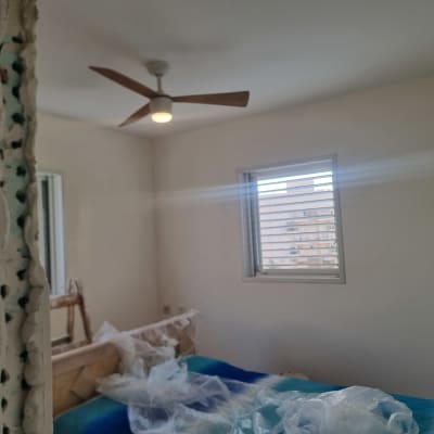 חדר בשיפוץ עם מאוורר תקרה, חלון וסולם.