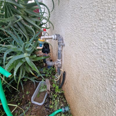 צינור מים מחובר לקיר עם ברזים וצינור ירוק