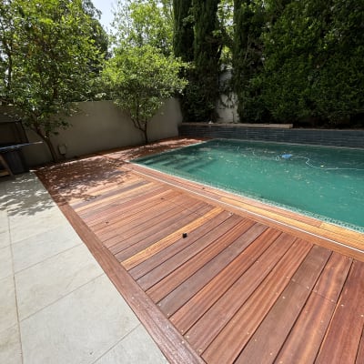 דק עץ ליד בריכה עם עצים ברקע